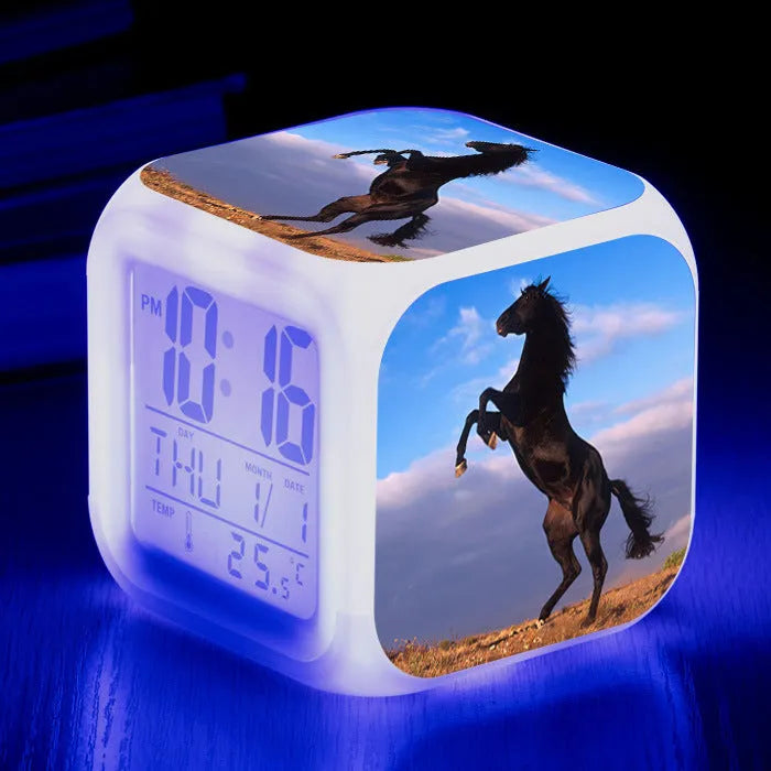 Square cartoon-style LED alarm clock with colour-changing display showing digital time and temperature