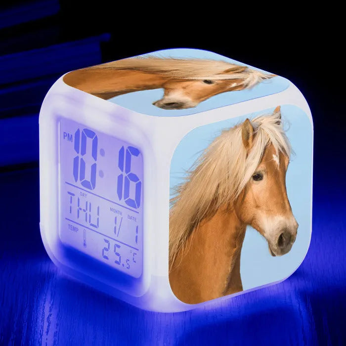 Square cartoon-style LED alarm clock with colour-changing display showing digital time and temperature