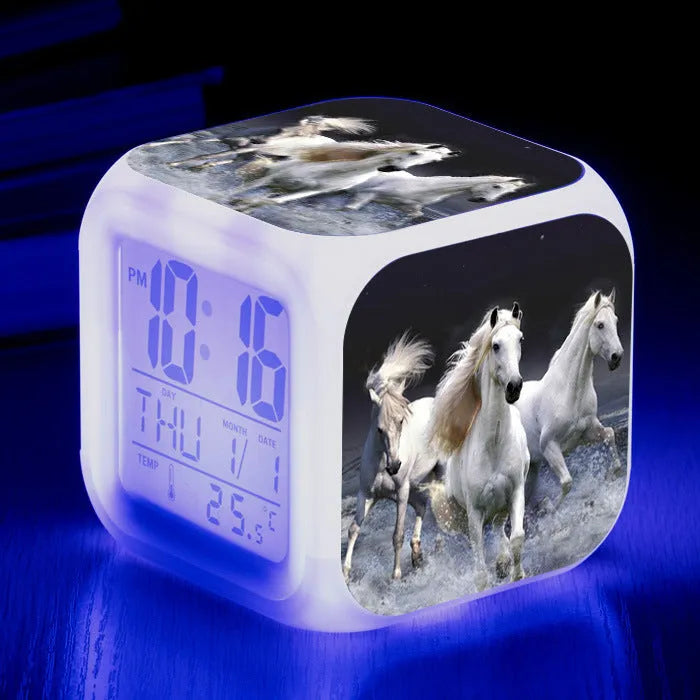 Square cartoon-style LED alarm clock with colour-changing display showing digital time and temperature