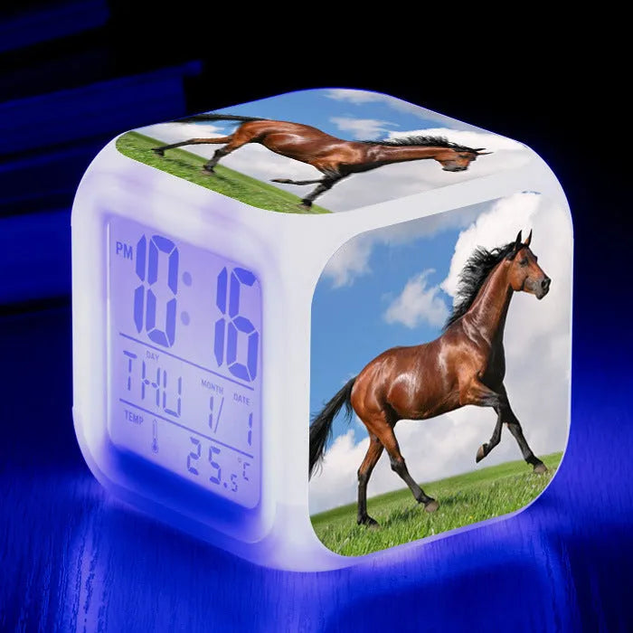 Square cartoon-style LED alarm clock with colour-changing display showing digital time and temperature