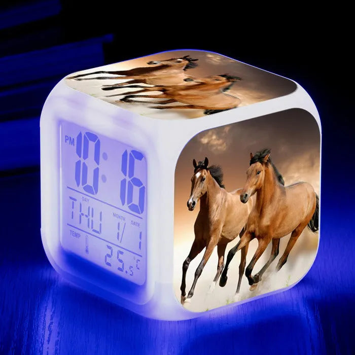 Square cartoon-style LED alarm clock with colour-changing display showing digital time and temperature