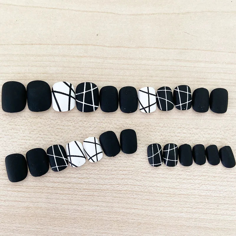 Fake nail patch with matte black and white lines design on a white background
