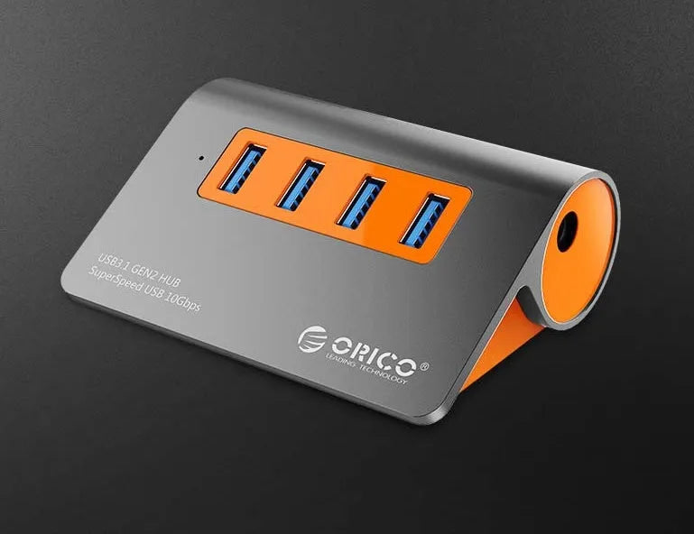 Dark grey aluminium USB-C hub with orange accents showing four USB 3.1 ports and detachable cable