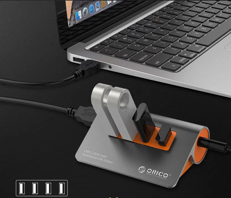 Dark grey aluminium USB-C hub with orange accents showing four USB 3.1 ports and detachable cable