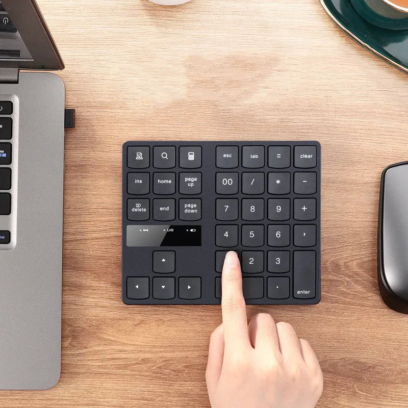 Black wireless 35-key numeric keyboard with USB receiver and charging cable on desk