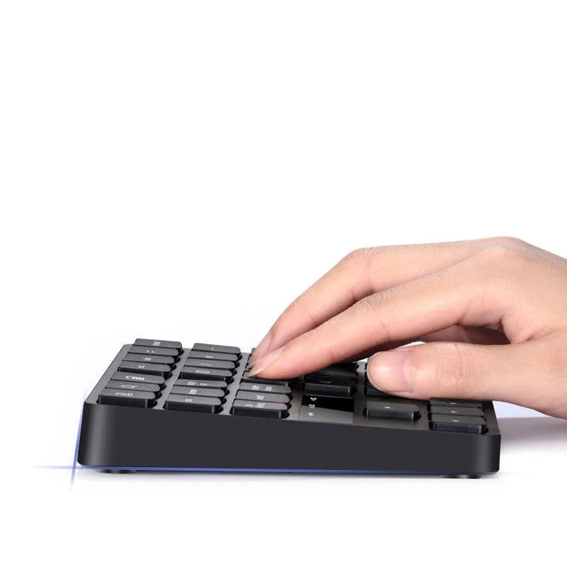Black wireless 35-key numeric keyboard with USB receiver and charging cable on desk