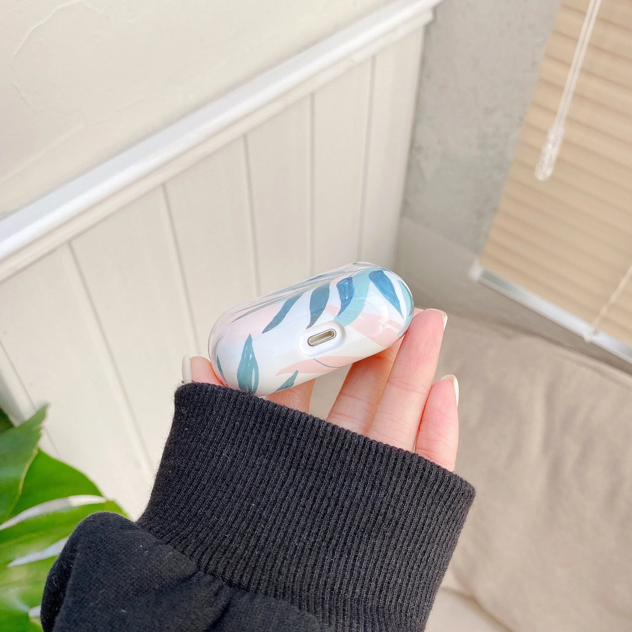 Blue soft TPU AirPods case with painted tropical banana leaves design.