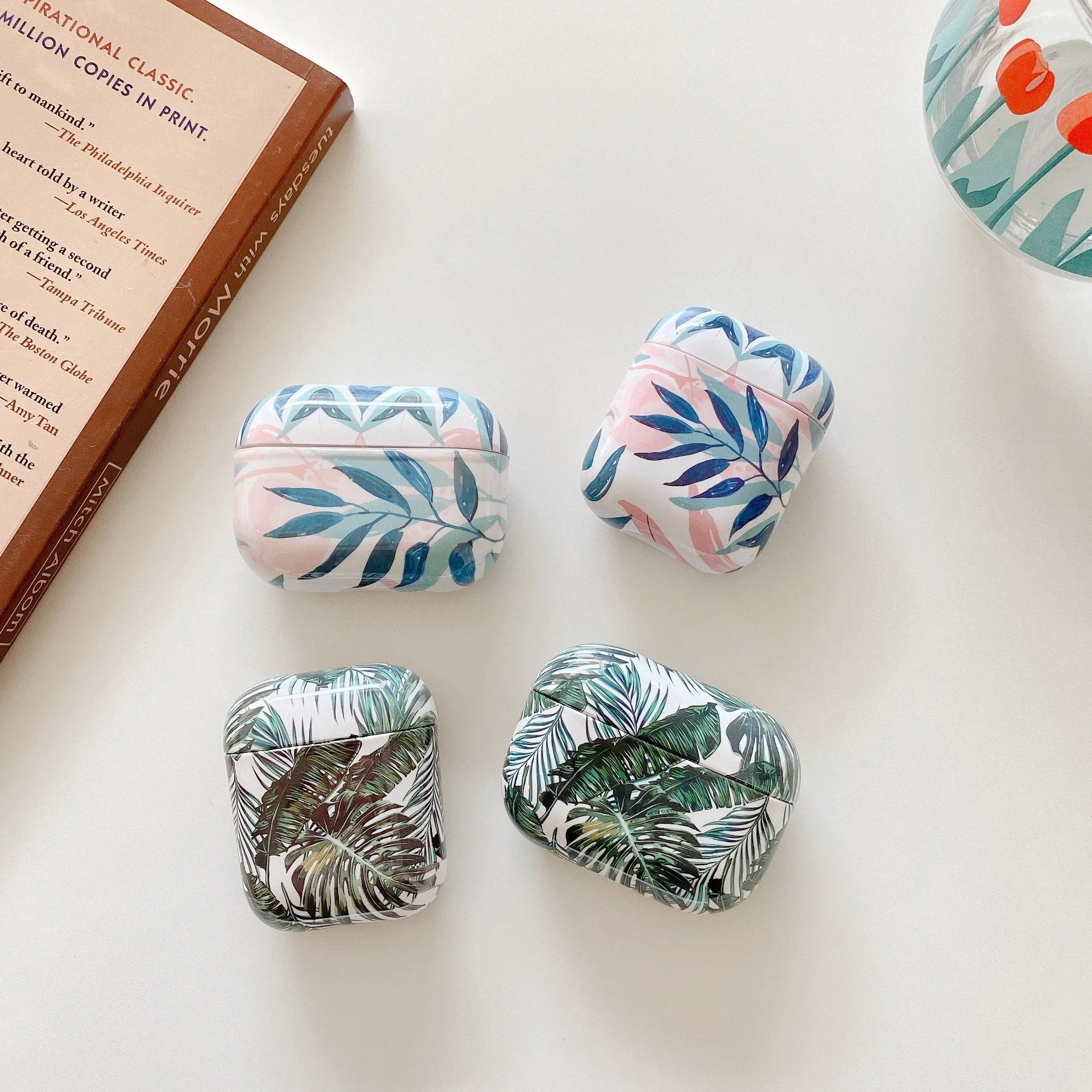 Blue soft TPU AirPods case with painted tropical banana leaves design.