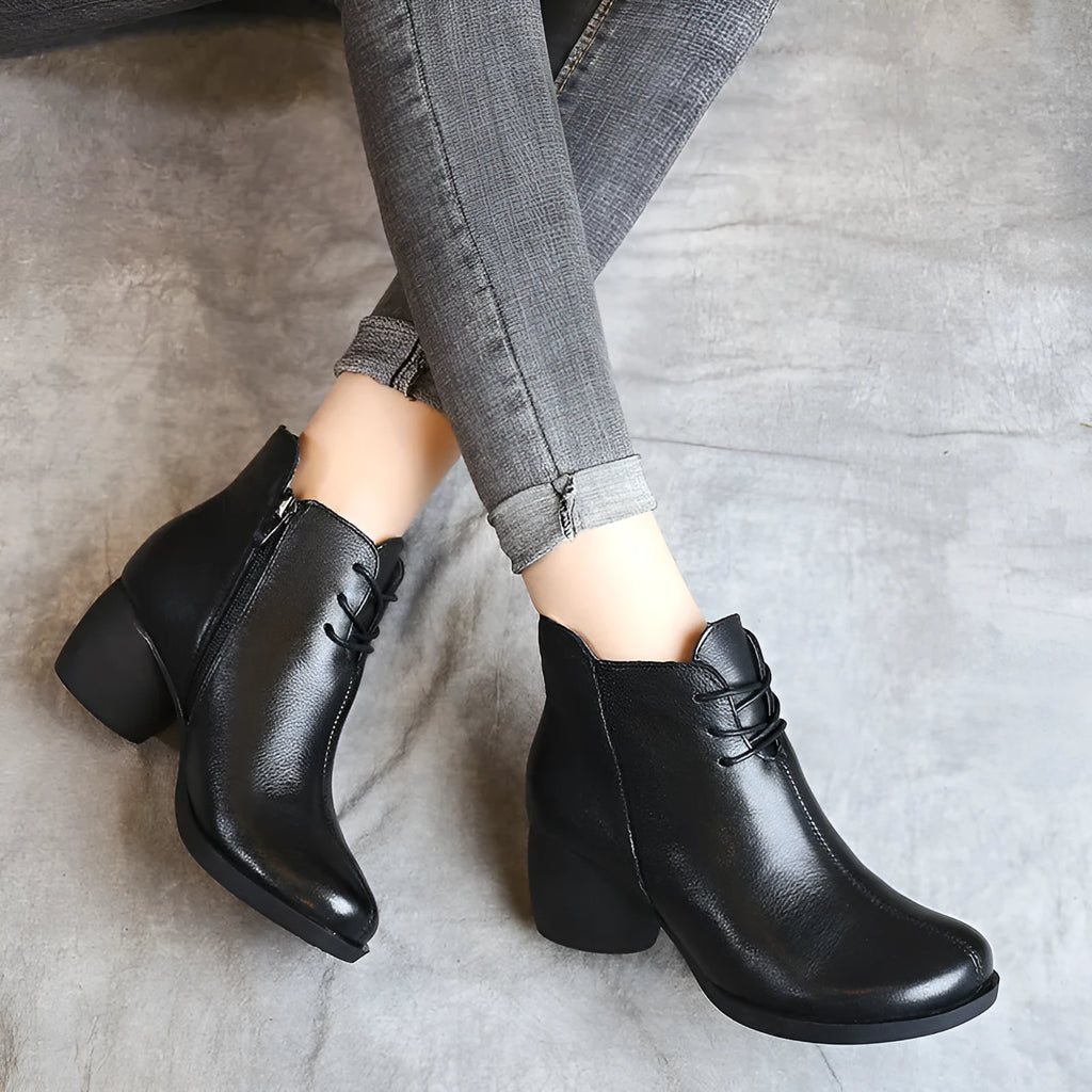 Women's black leather Martin boots with a thick mid heel and round toe on a light background.