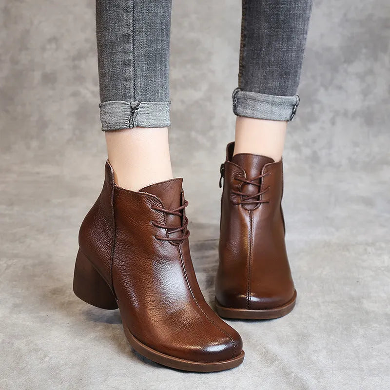Women's black leather Martin boots with a thick mid heel and round toe on a light background.