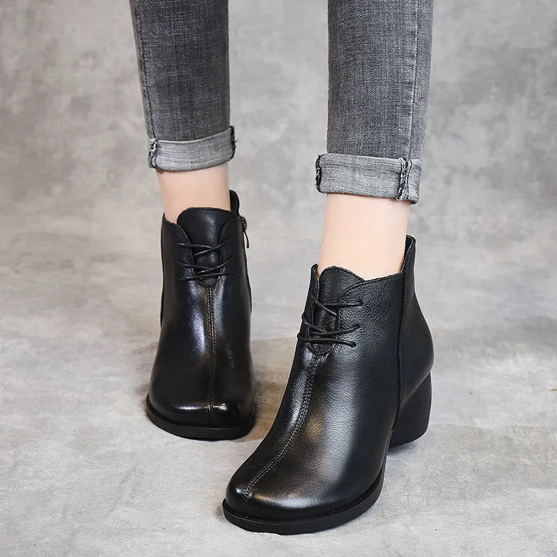 Women's black leather Martin boots with a thick mid heel and round toe on a light background.