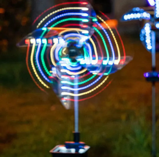 Solar wind spinner light with LED illumination spinning on lawn at dusk, showing IP65 waterproof aluminium and ABS construction