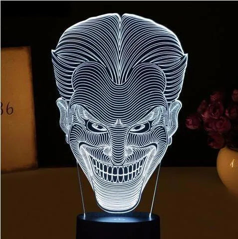 A 3D LED table lamp with a colourful acrylic panel on a square base, showing multiple colour options.