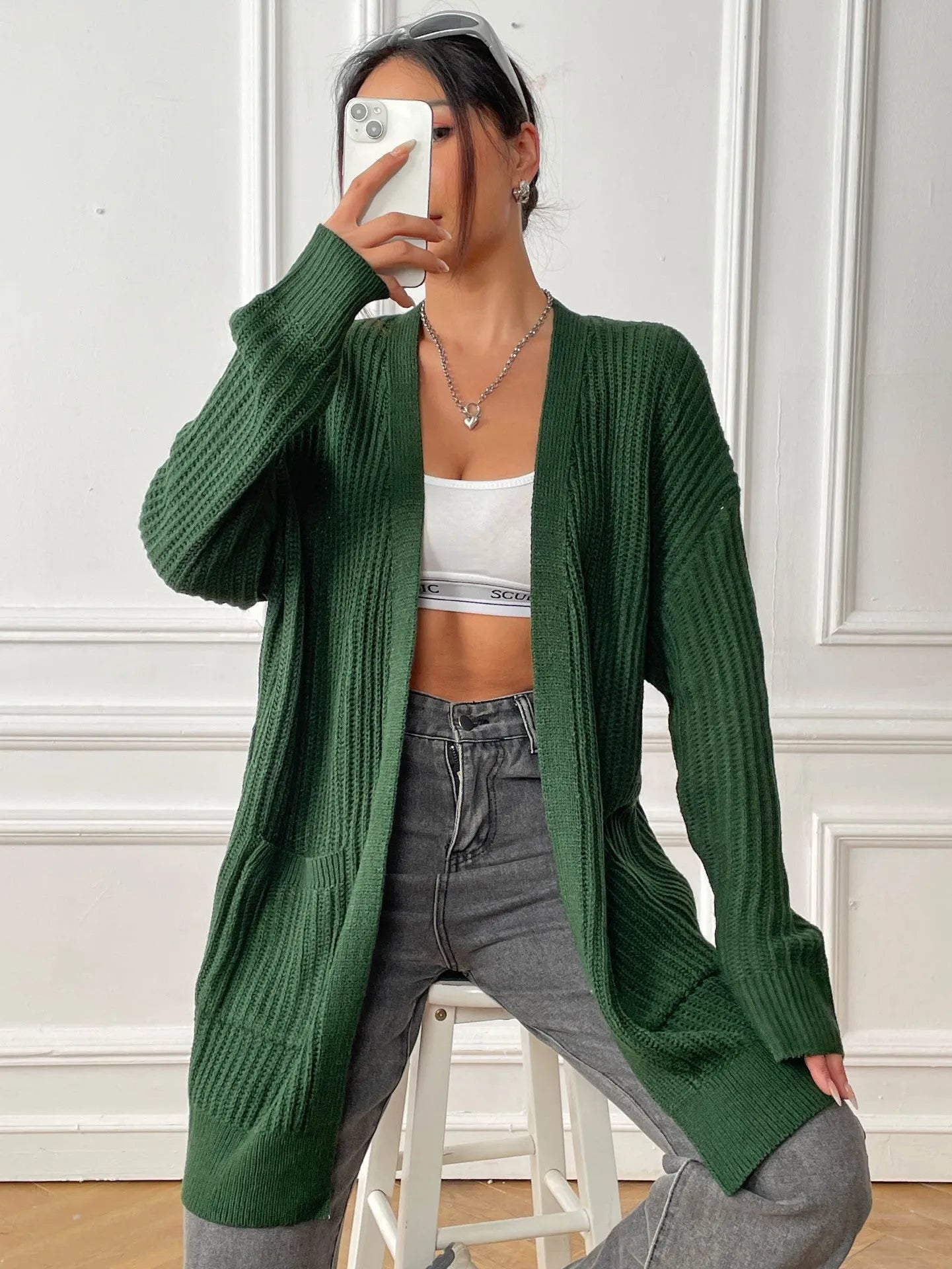 Women's dark green loose fit acrylic cardigan sweater with double pockets and long sleeves.