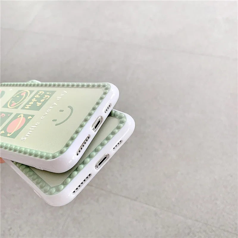 Green TPU iPhone case with geometric smiley face design and polka dot frame on a phone.