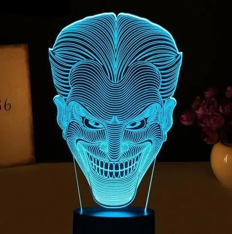 A 3D LED table lamp with a colourful acrylic panel on a square base, showing multiple colour options.