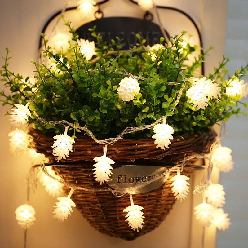 Battery-powered warm white LED pine cone fairy lights draped decoratively on a surface.