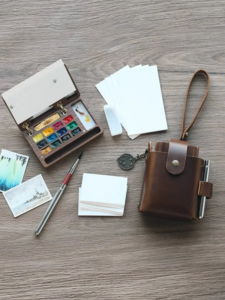 Miniature wooden watercolour paint box on a table, showcasing its compact size and walnut finish.