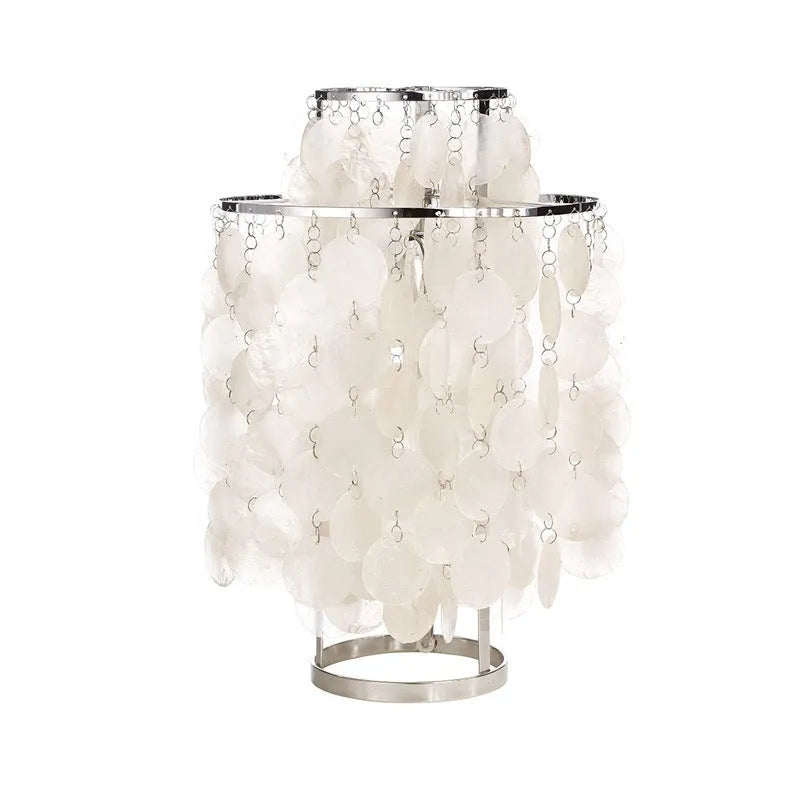 Modern shell-shaped bedside table lamp in chrome metal finish on a wooden surface.