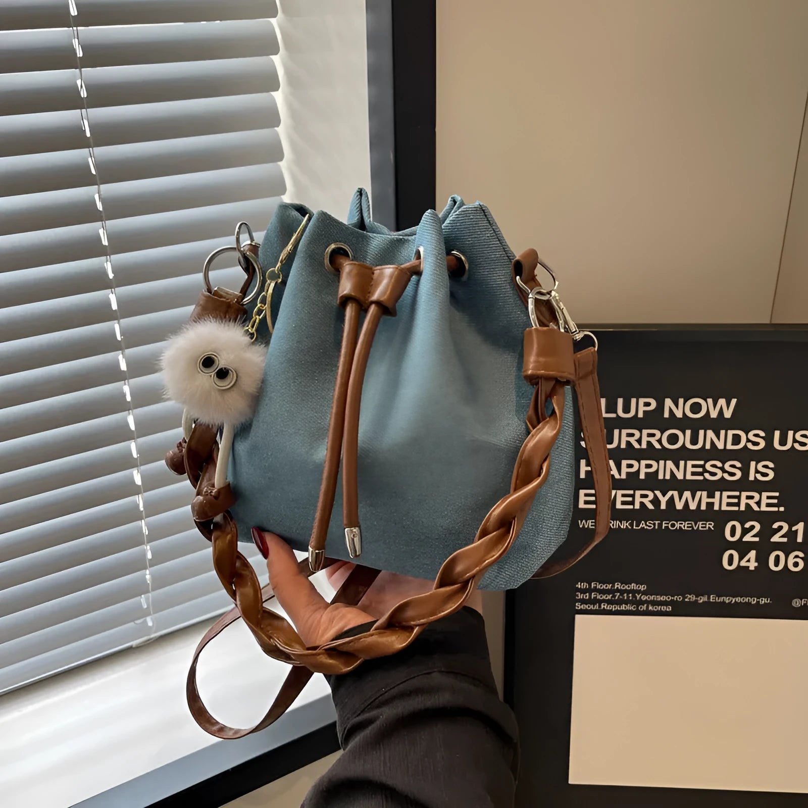 Blue one-shoulder cross body bucket bag with messenger style design and synthetic leather lining