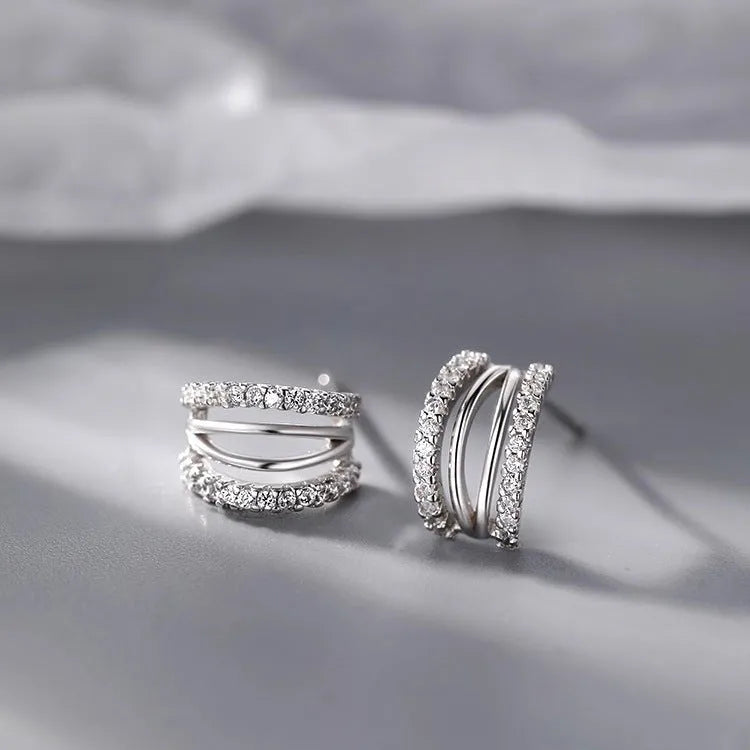 A pair of geometric-designed 925 sterling silver earrings with needle posts on a plain background.