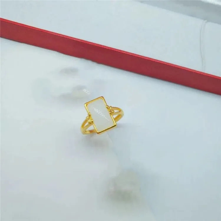 Adjustable gold-plated brass ring with a central gemstone inlay on a model's finger.