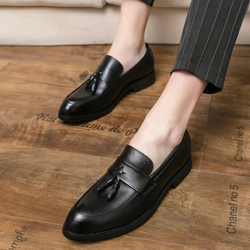 Men's black slip-on business casual shoes with a tassel detail and pointed toe.