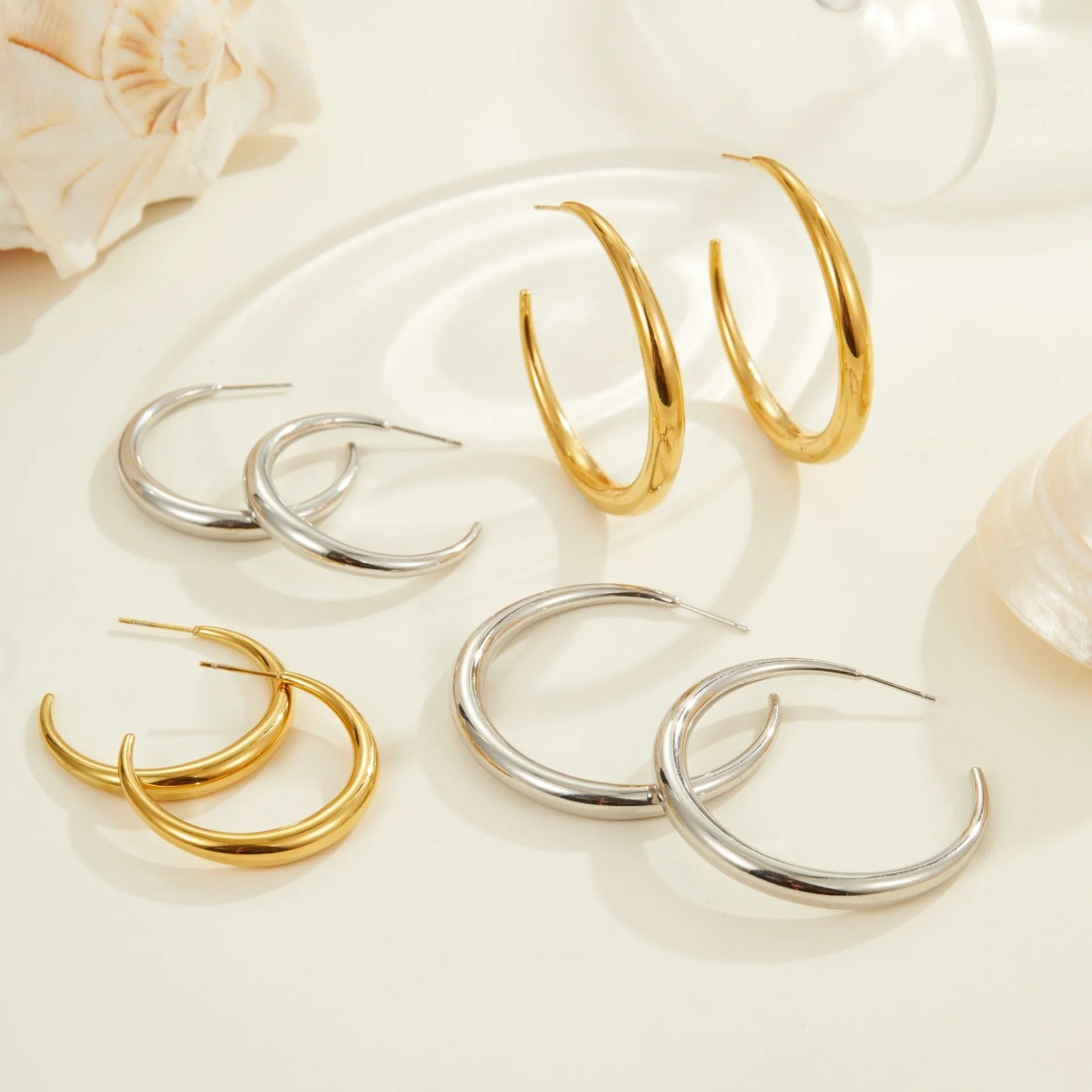 Titanium steel hoop earrings in gold and steel finishes, available in large and small sizes with simple geometric design