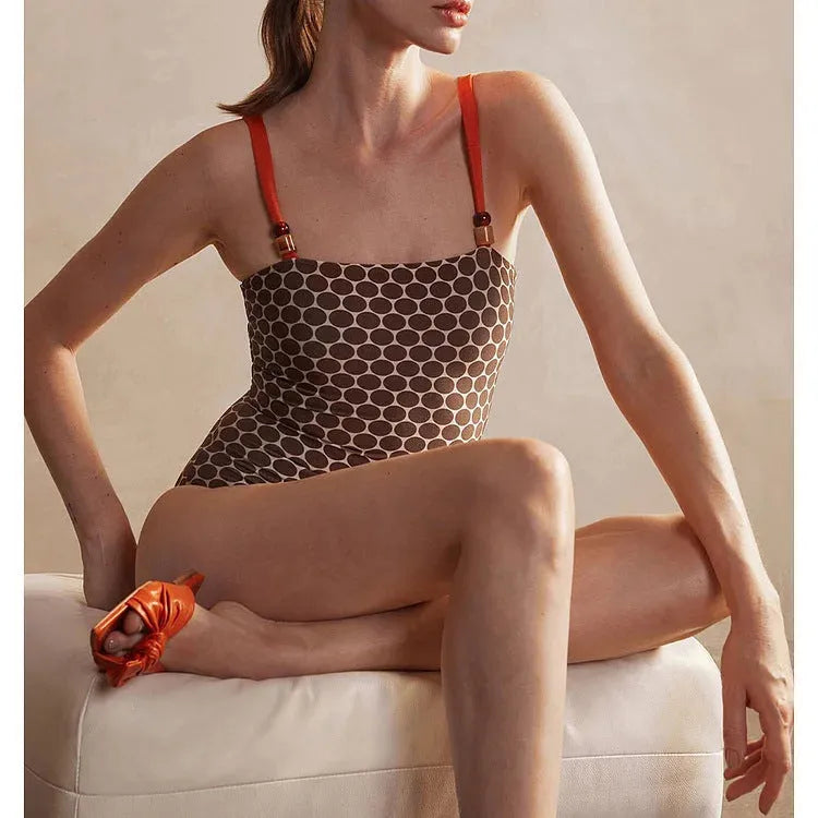 Women's dot-pattern one-piece swimsuit with matching wrap skirt set on a hanger.