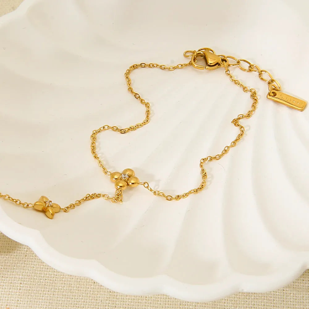 Gold-coloured stainless steel women's bracelet with eight-pointed star shape and floral decorative elements