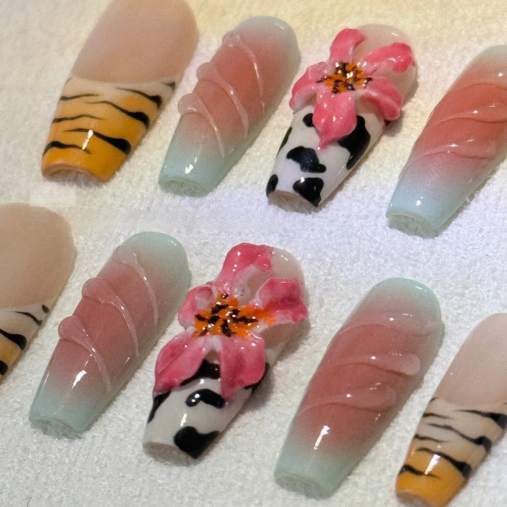 Zebra pattern and Lily hand carving design on a set of long, decorative false nails.