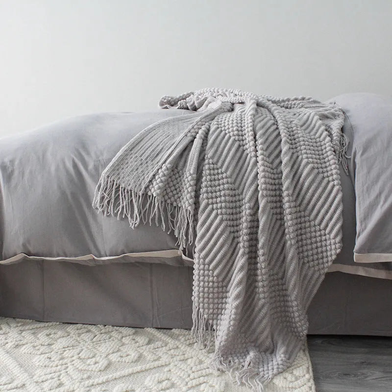 Light grey polyester throw blanket draped over a sofa, showing its size.