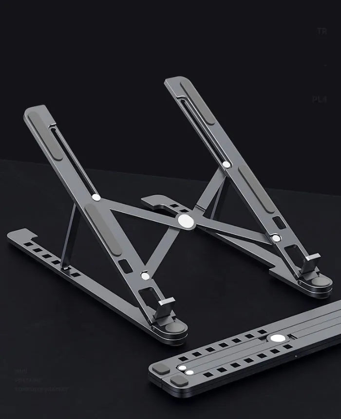 Aluminum foldable laptop stand in silver colour, shown adjusted to an elevated height with a laptop on top.