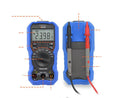 Handheld digital multimeter on a workbench with test probes.
