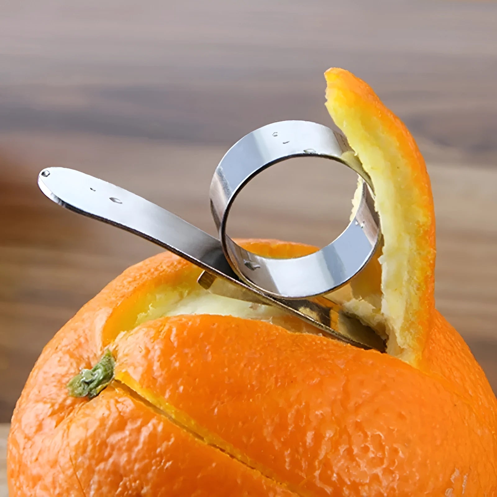 Silver stainless steel orange peeler ring on a citrus fruit