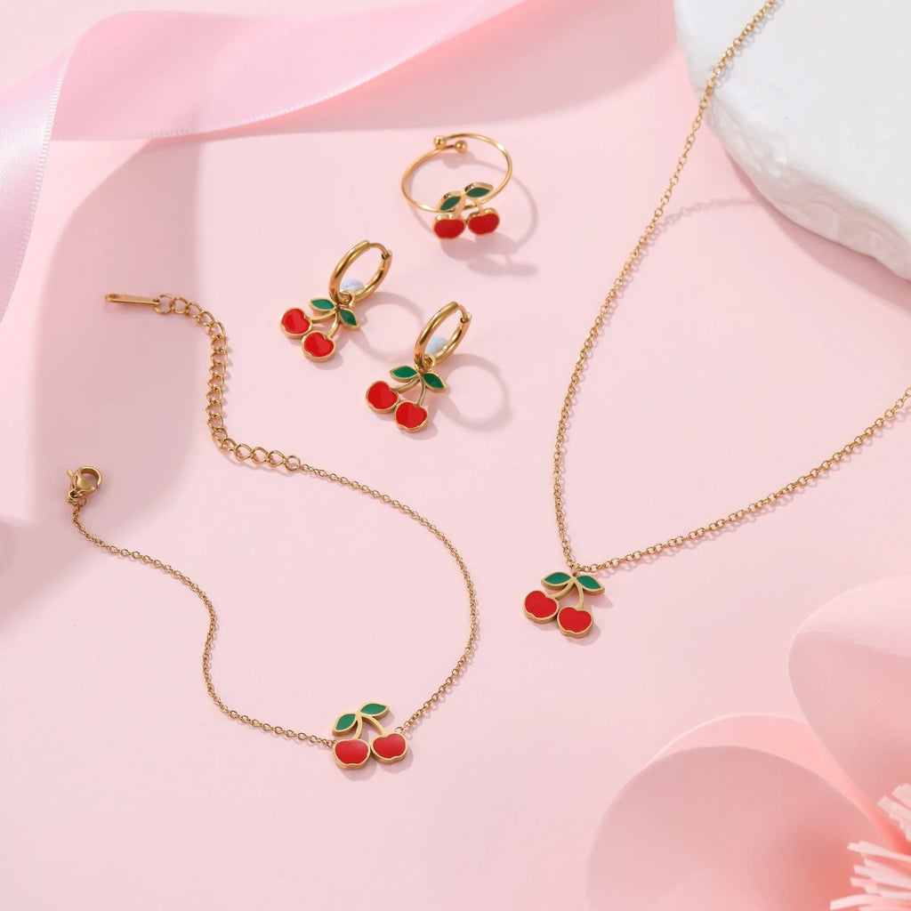 Cherry jewellery set showing necklace, bracelet, earrings, and ring with stainless steel construction and cherry motifs