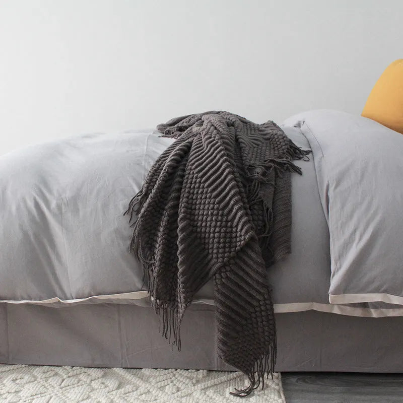 Light grey polyester throw blanket draped over a sofa, showing its size.
