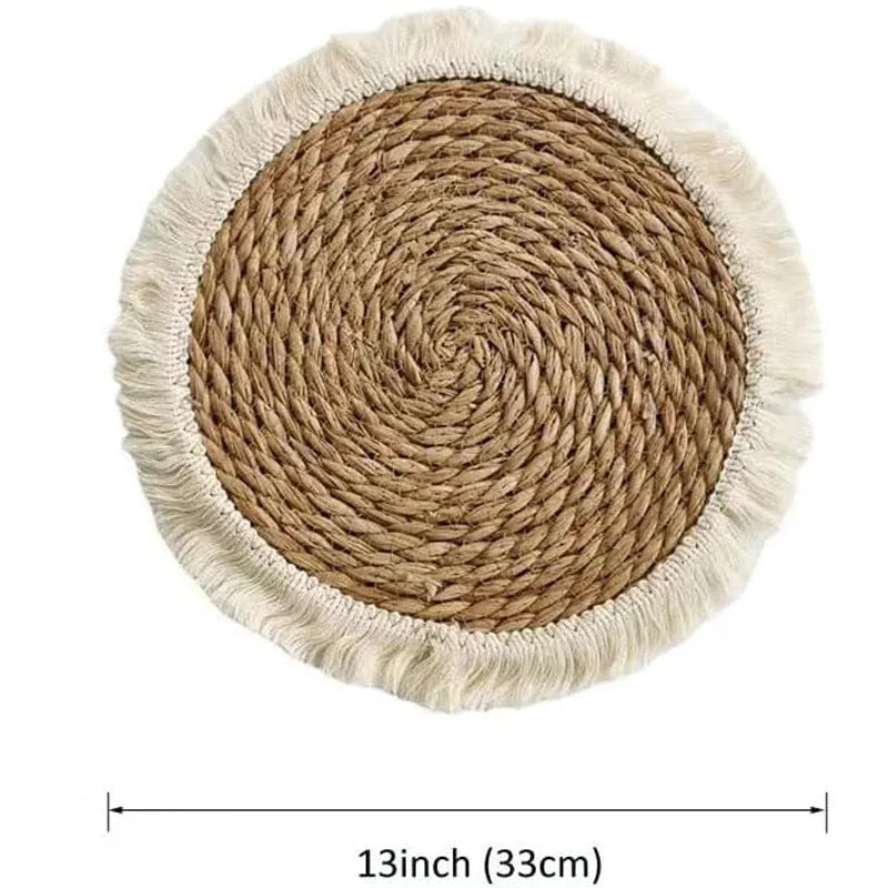 Round natural papyrus straw placemat with decorative tassel edge on a wooden table.