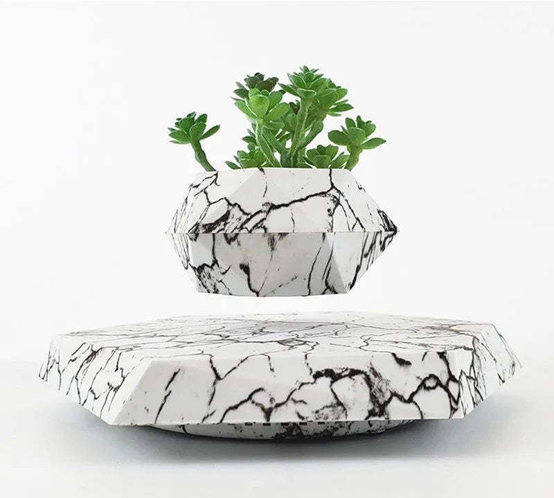 Small marble-colour magnetic levitating plant pot rotating above its base