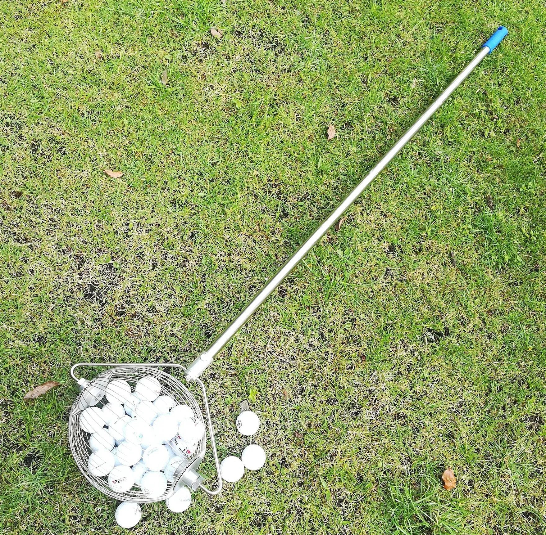 Metallic coloured golf ball picker made from stainless steel on a green