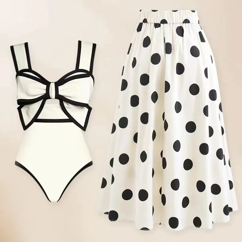 Women's black one-piece swimsuit with attached beach dress skirt featuring bow detail