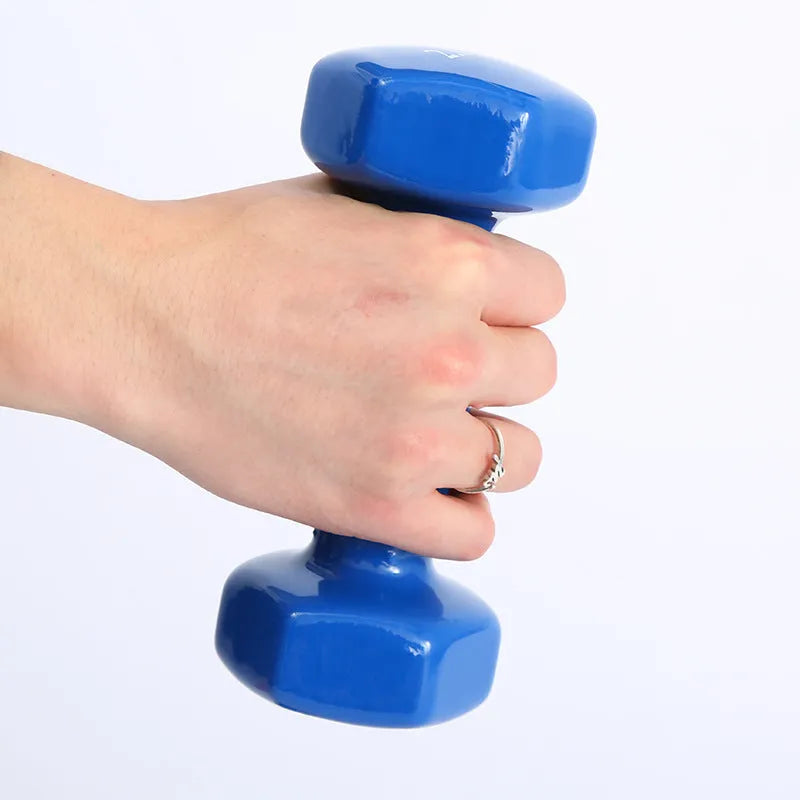 A set of bright green and pink plastic fitness dumbbells on a wooden floor.