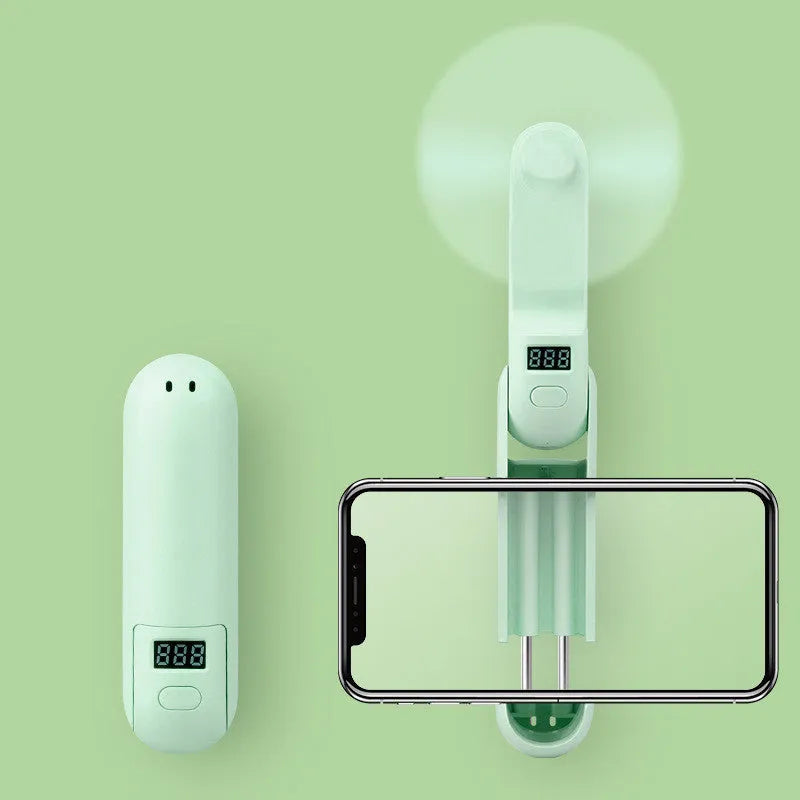 Green folding mini portable fan with USB cable on a white desk