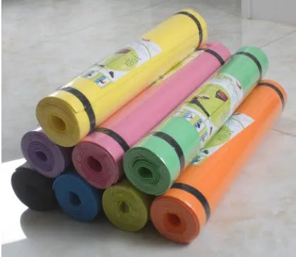 Red EVA fitness yoga mat with rolled edge showing thickness, laid flat on a wooden floor.