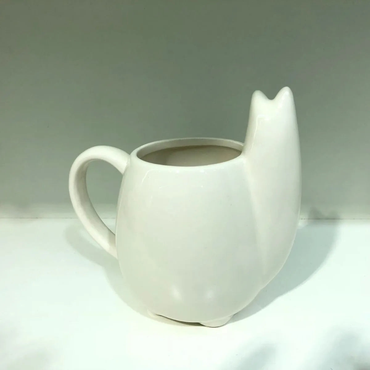 White ceramic mug with handle featuring a cartoon alpaca pattern on the side