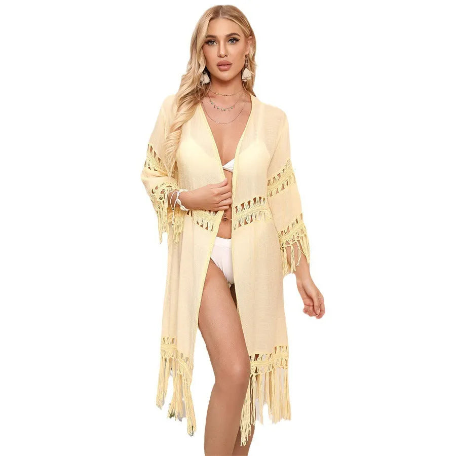 Women's hand-crocheted acrylic beach cardigan in water green with tassel details, laid flat.