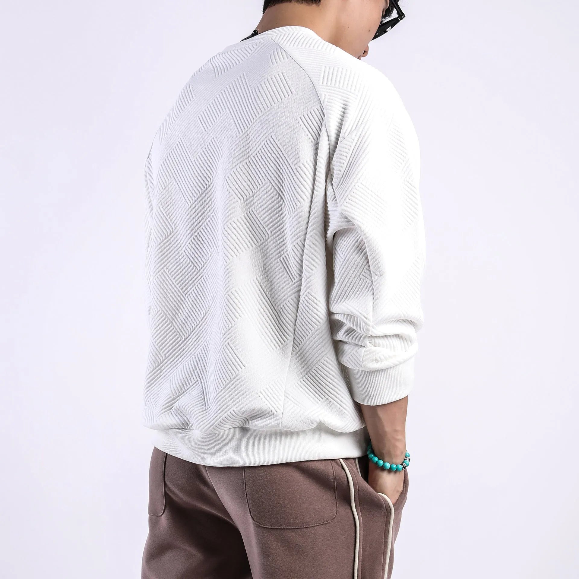 Man wearing a loose-fit, solid-colour twill jacquard long-sleeved sweater with a round neck.