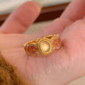 Geometric open ring for women with pink crystal enamel decoration on a gold-toned band.