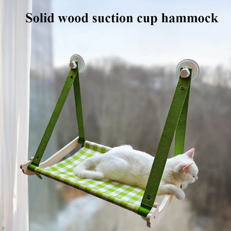 Pink wooden cat hammock bed with suction cups attached to a window, showing a cat lying on the linen mat.