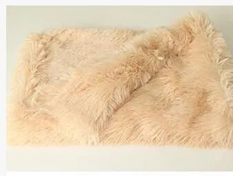 Soft grey plush pet blanket for dogs shown on a floor next to a kennel.